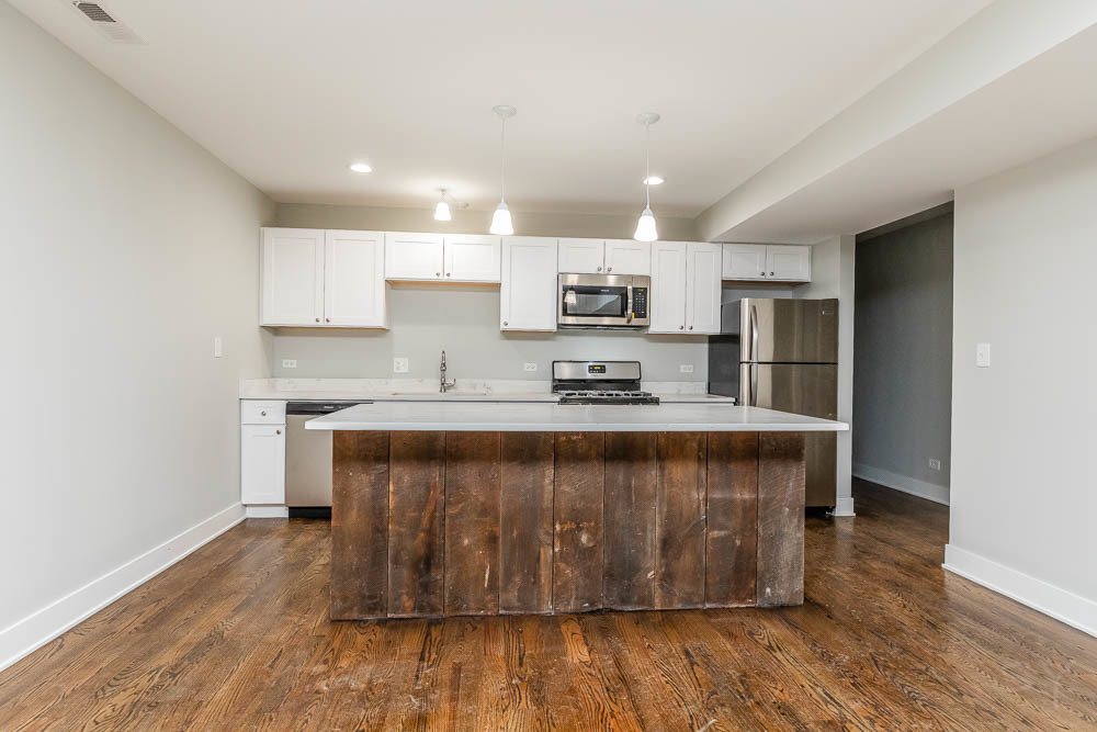 2109 West 18th Place Chicago, IL 60608 - Photo 7 of 63 a open kitchen with kitchen island a sink dishwasher a stove and a refrigerator with wooden floor