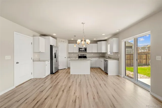 a kitchen with stainless steel appliances kitchen island wooden floors and refrigerator