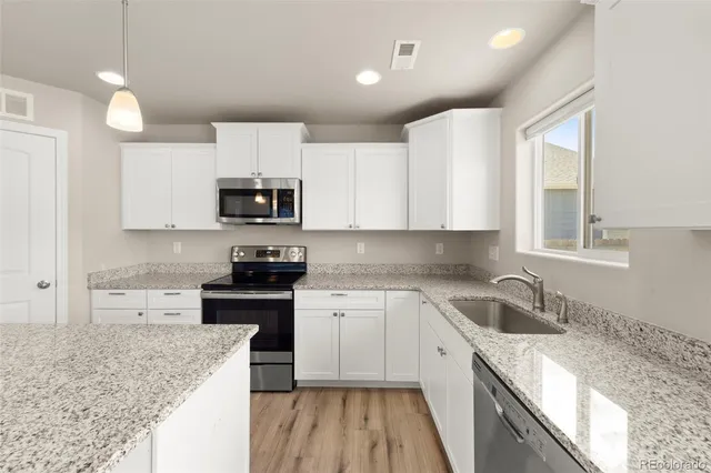 a kitchen with granite countertop white cabinets and stainless steel appliances