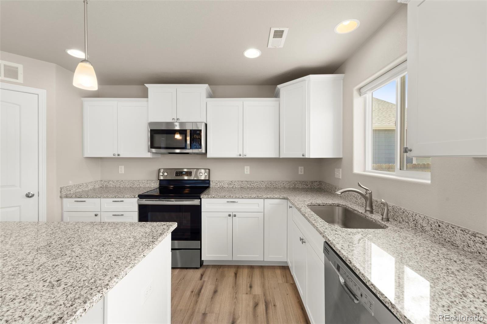 7721 Berwyn Loop Peyton, CO 80831 - Photo 19 of 35 a kitchen with granite countertop white cabinets and stainless steel appliances