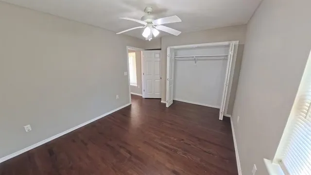 a view of an empty room with a window and wooden floor