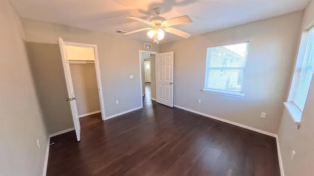 a view of an empty room with window and wooden floor