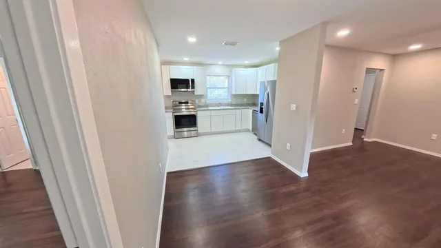 a view of a kitchen with white cabinets and wooden floor