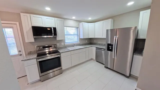 a kitchen with stainless steel appliances granite countertop a refrigerator stove a sink and a microwave