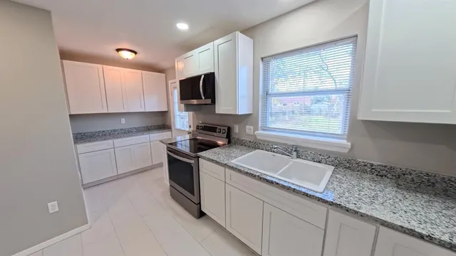 a kitchen with granite countertop a sink stainless steel appliances a window and a counter top space