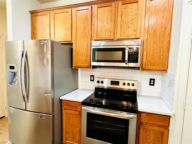 a kitchen with stainless steel appliances granite countertop a refrigerator microwave and stove top oven