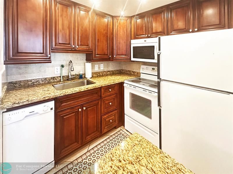 a kitchen with granite countertop wooden cabinets and white appliances