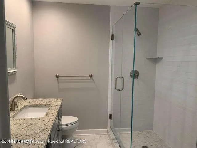 a bathroom with a granite countertop toilet and a sink