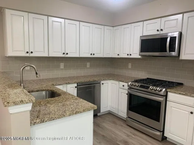 a kitchen with white cabinets and stainless steel appliances