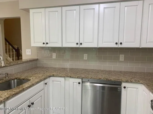 a kitchen with granite countertop white cabinets and sink