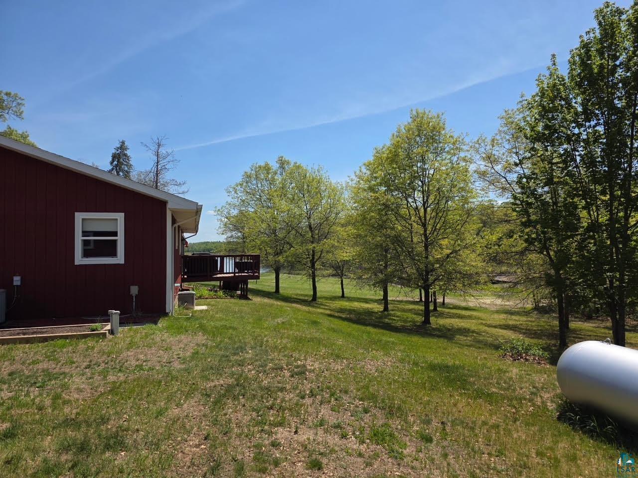 11702 East Mail Road Gordon, WI 54838 - Photo 6 of 49 Expansive green space featuring a large wooden deck, mature trees, and a red-sided structure