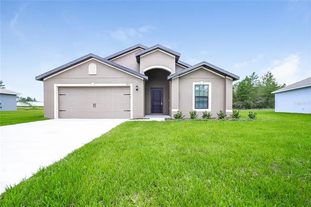 a view of a house with a big yard and large trees