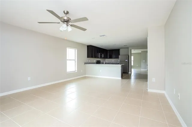 a view of a livingroom with a ceiling fan & kitchen space with a window