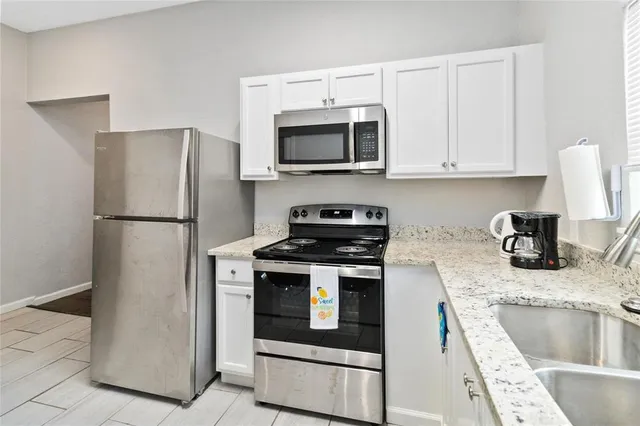 a kitchen with granite countertop a refrigerator stove and sink