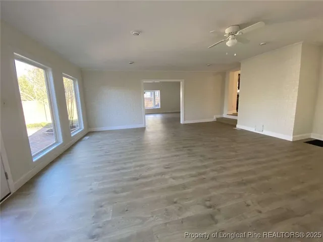 a view of an empty room with window and wooden floor