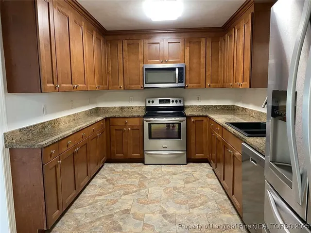 a kitchen with stainless steel appliances granite countertop a stove a sink and a microwave