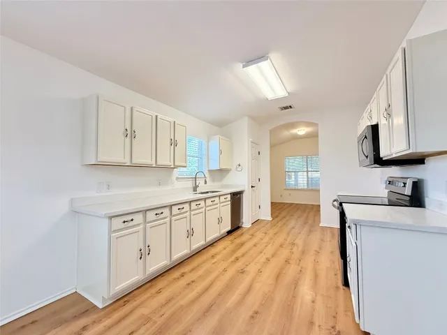 a large kitchen with cabinets stainless steel appliances a sink and a stove