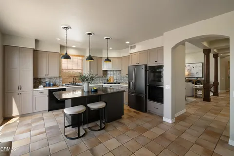 a kitchen with stainless steel appliances granite countertop a sink a stove a refrigerator and island with wooden floor