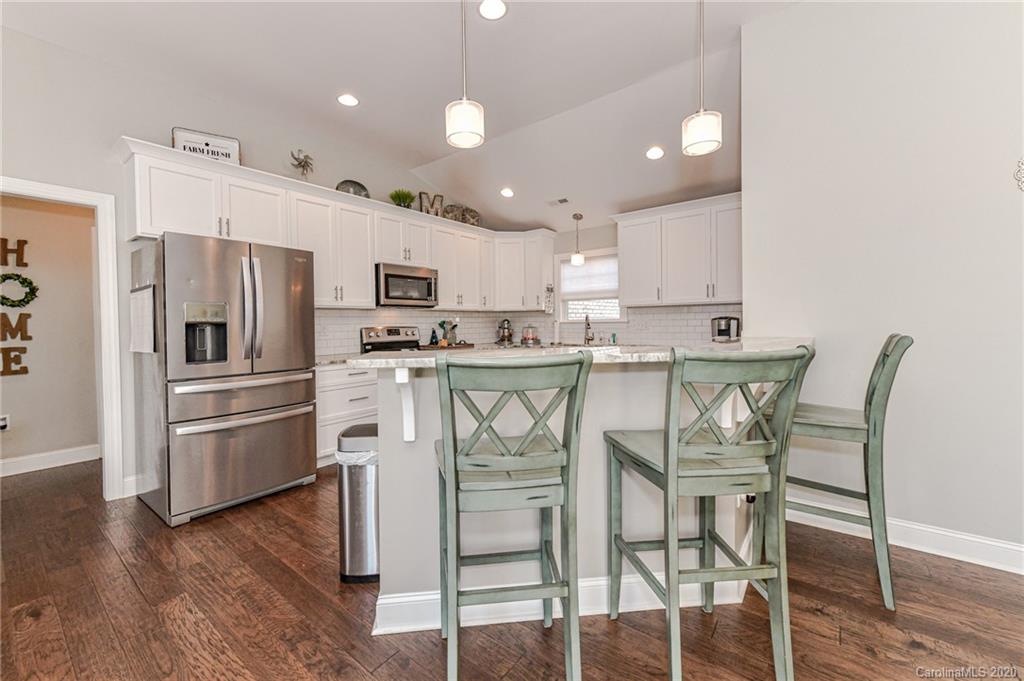 3113 East Brief Road Monroe, NC 28110 - Photo 14 of 42 a kitchen with stainless steel appliances granite countertop a stove a refrigerator a microwave oven with a dining table and chairs