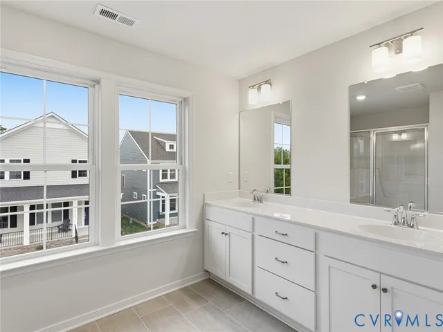 a spacious bathroom with double vanity a sink a mirror and a shower
