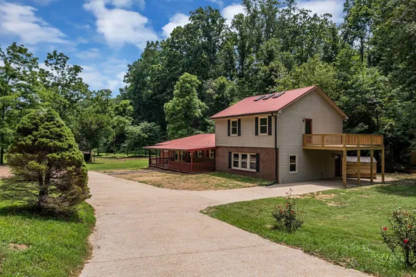 a front view of a house with a garden and trees