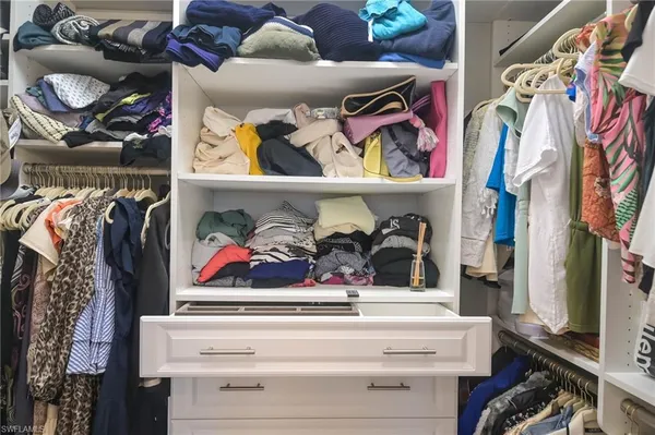 a view of walk in closet with clothes and shoes