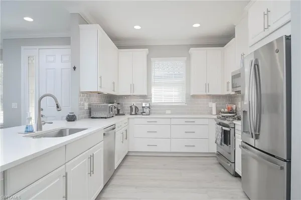 a kitchen with white cabinets stainless steel appliances and a window