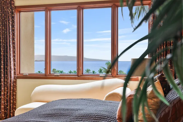 a bedroom with a bed lamp and a large window with the outer view