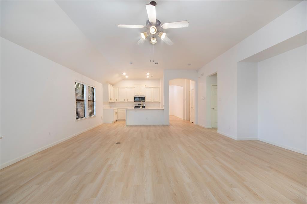 549 Hickory Lane Fate, TX 75087 - Photo 15 of 38 Unfurnished living room featuring a ceiling fan, arched walkways, light wood-type flooring, and vaulted ceiling