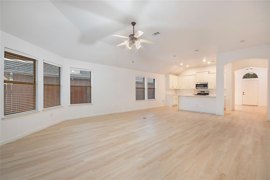 549 Hickory Lane Fate, TX 75087 - Photo 16 of 38 Unfurnished living room with arched walkways, lofted ceiling, a ceiling fan, and light wood-type flooring