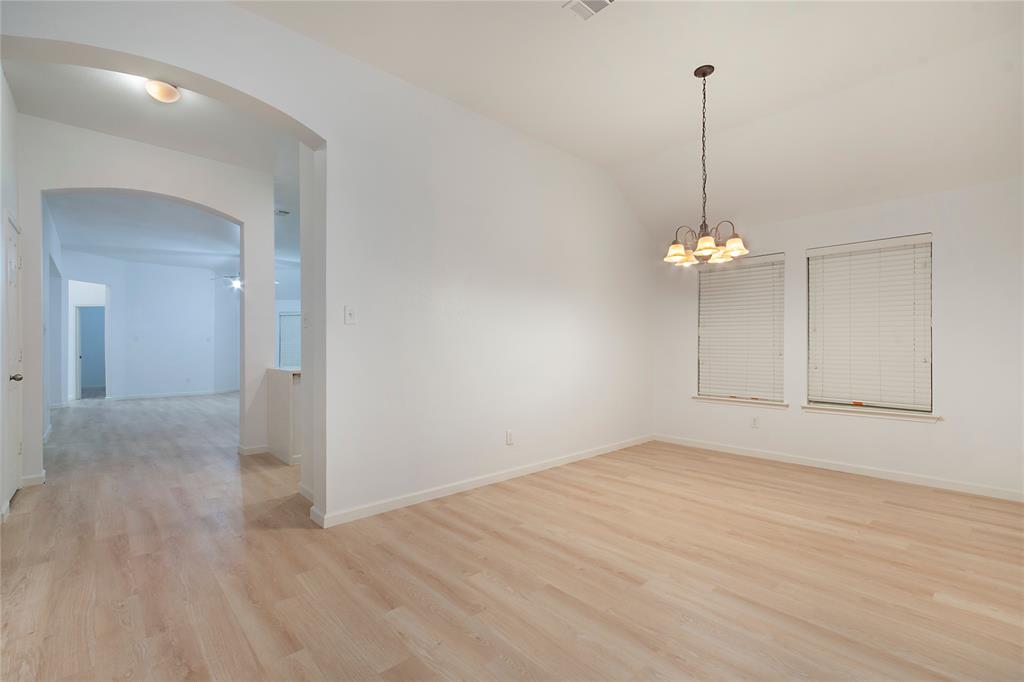549 Hickory Lane Fate, TX 75087 - Photo 7 of 38 Unfurnished dining area featuring lofted ceiling, suspended lighting, light wood finished floors, and arched walkways