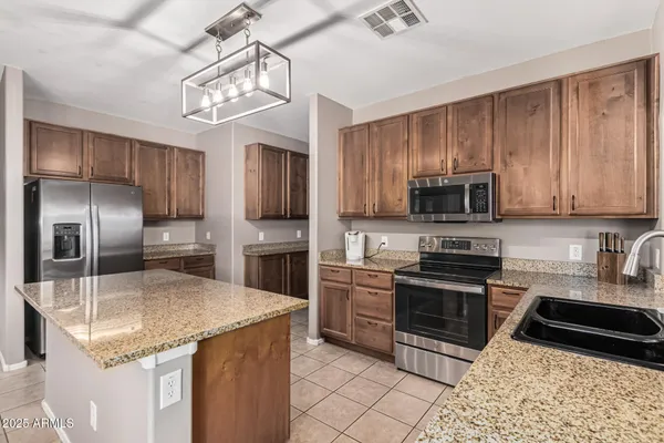 a kitchen with granite countertop a refrigerator a sink a stove top oven and a center island