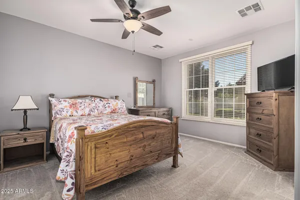 a bedroom with a bed and a flat tv screen on dresser