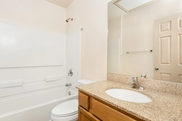 a bathroom with a granite countertop sink toilet mirror and shower