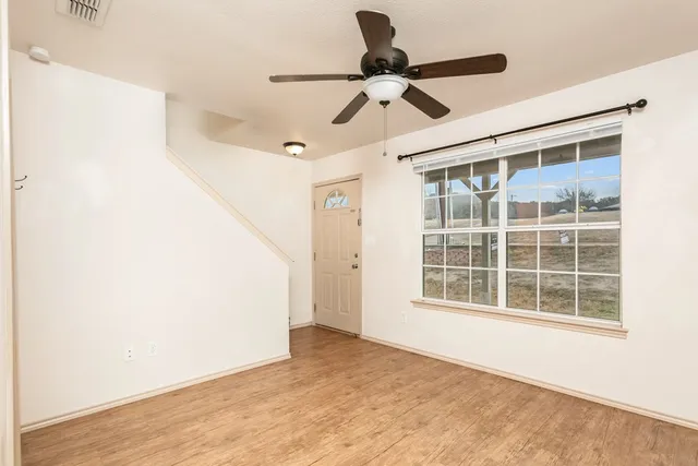 a view of empty room with wooden floor and fan