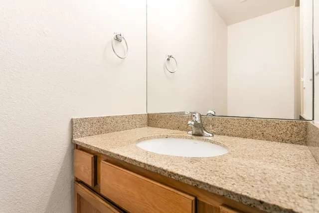 a bathroom with a granite countertop sink and a mirror