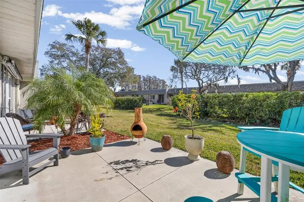 a view of a patio with chairs and a table and chairs under an umbrella