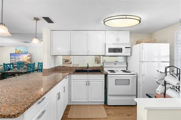 a kitchen with stainless steel appliances granite countertop a stove a refrigerator and a dining table with wooden floor