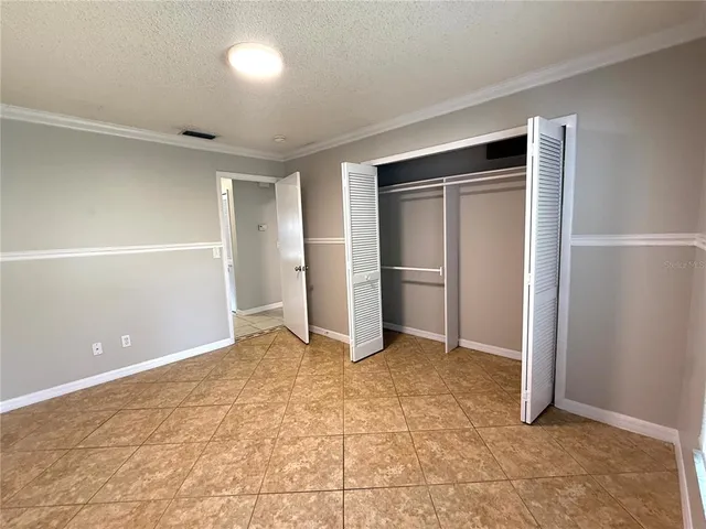 an empty room with closet and a chandelier fan