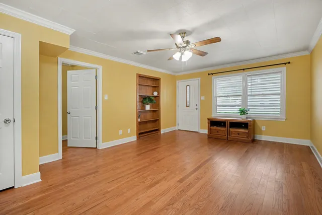a view of an empty room with a window and wooden floor