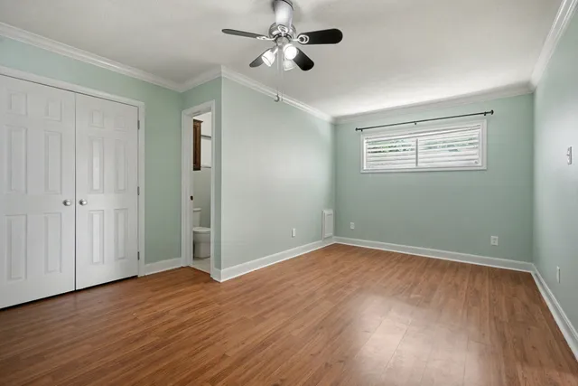 an empty room with wooden floor ceiling fan and windows