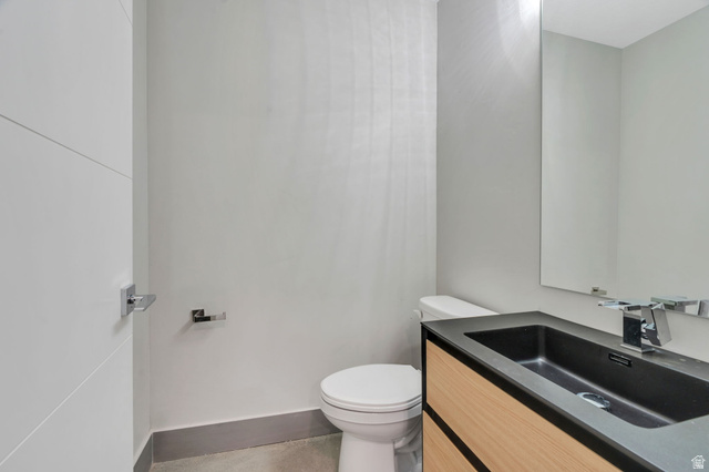 7045 South 300 East Midvale, UT 84047 - Photo 34 of 49 Modern bathroom featuring a wood-finish vanity with a black integrated sink, a sleek wall-mounted mirror, and chrome fixtures