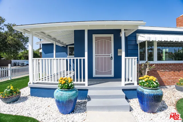 a front view of a house with outdoor seating and covered with potted plants