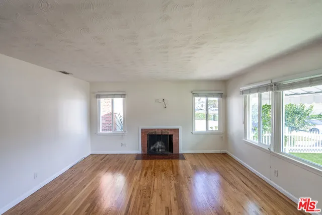 an empty room with wooden floor windows and fireplace