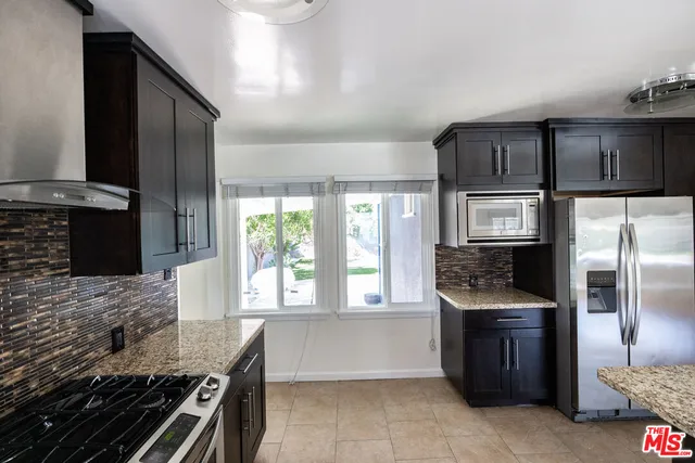 a kitchen with granite countertop a refrigerator and a stove top oven