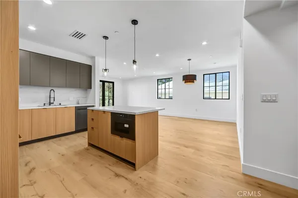 a kitchen with kitchen island a counter top space a sink stainless steel appliances and cabinets