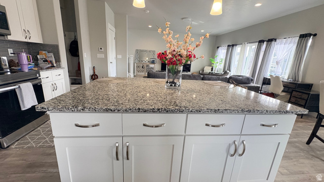 7889 Bristlecone Road Eagle Mountain, UT 84005 - Photo 10 of 42 Spacious kitchen island featuring a speckled countertop, white cabinetry with silver-tone hardware, and pendant lighting overhead