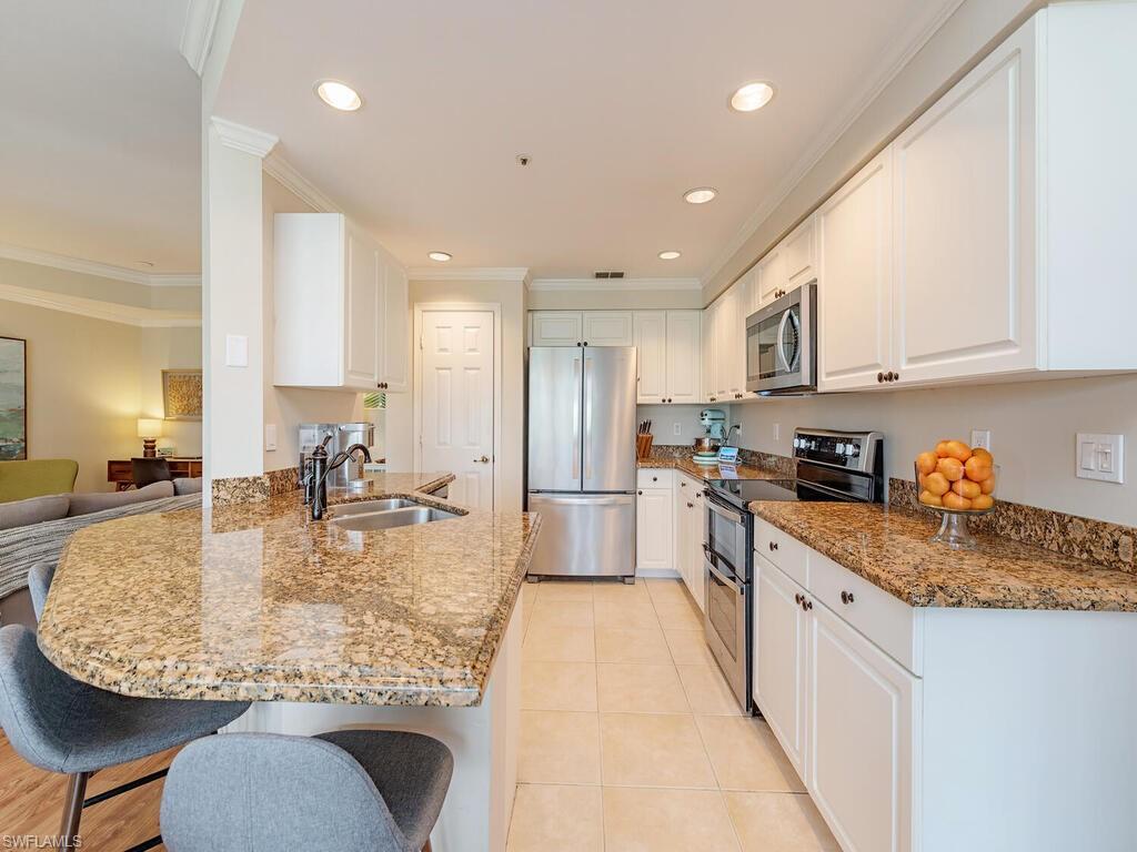 7756 Gardner Drive, Unit 102 Naples, FL 34109 - Photo 6 of 16 a kitchen with kitchen island granite countertop a large counter top stainless steel appliances and cabinets