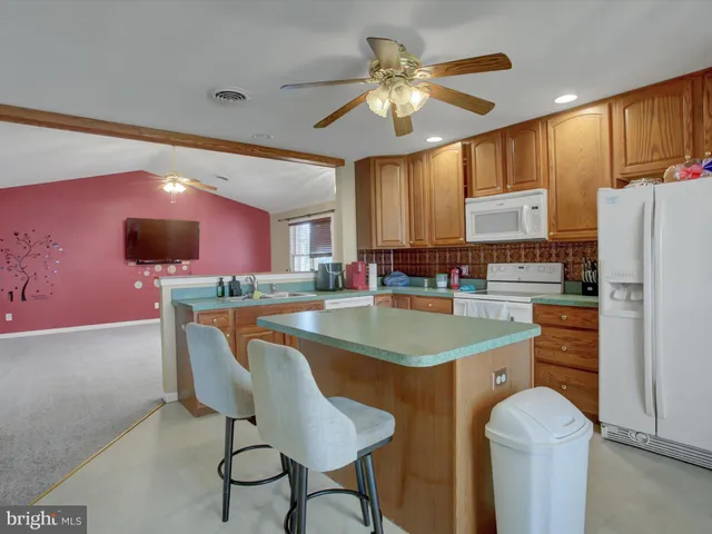 a kitchen with stainless steel appliances granite countertop a sink a stove a refrigerator cabinets and chairs