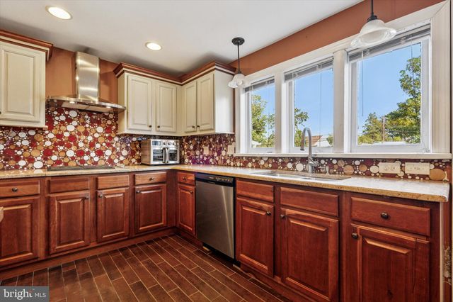 a kitchen with stainless steel appliances granite countertop wooden cabinets a sink and dishwasher with wooden floor